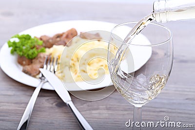 Pouring white wine and food background