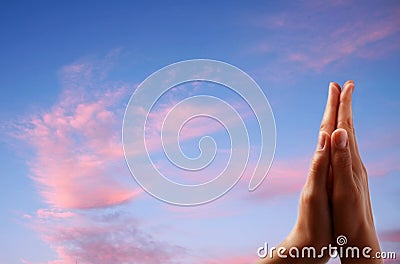 Praying hands on sky background