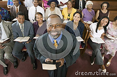 Preacher Holding Bible With Congregation Sitting In Church