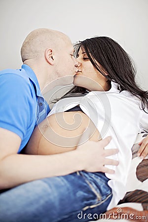 Pregnant couple kissing in bed