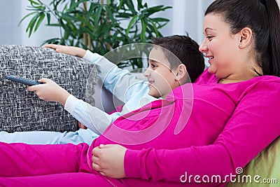 Pregnant mom and son watching television together