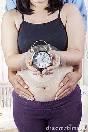 Pregnant mother and husband with clock