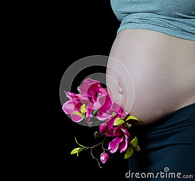 Pregnant woman on black background with hands on her belly
