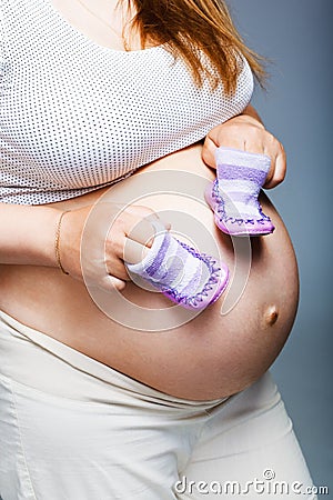 Pregnant woman holding pair of shoes