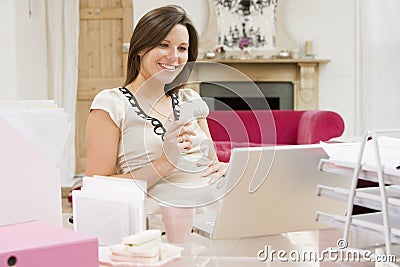 Pregnant woman in home office with laptop eating