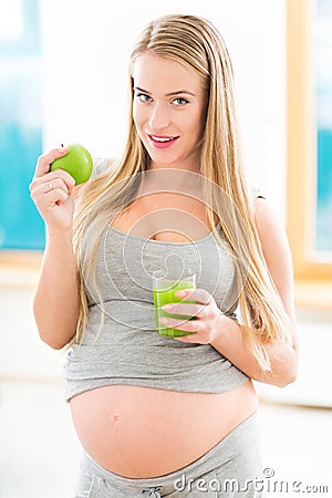 Pregnant woman with juice and apple