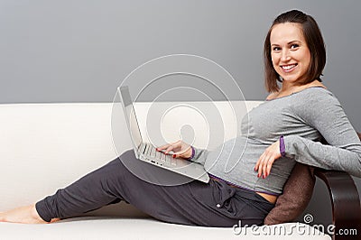 Pregnant woman with laptop at home