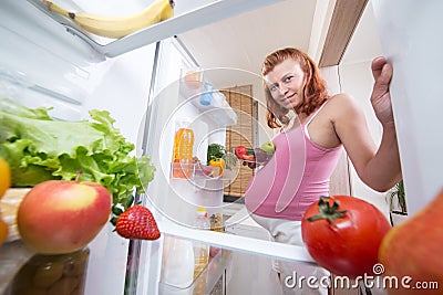 Pregnant woman and refrigerator with health food vegetables