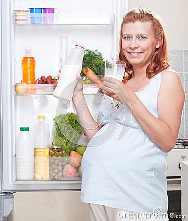 Pregnant woman and refrigerator with health food vegetables