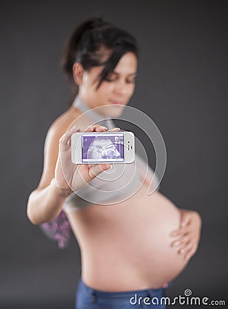 Pregnant woman showing her pregnancy ultrasound on smartphone