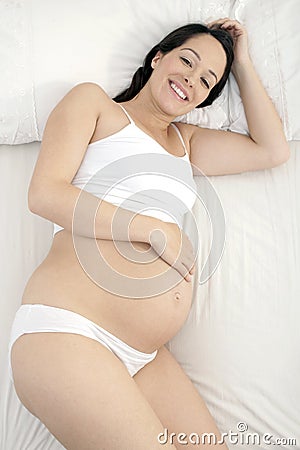 Pregnant woman smiling in bed