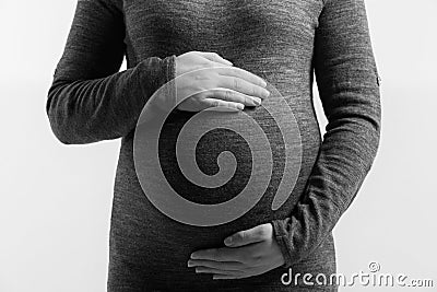 Pregnant woman touching her belly with hands, on white background