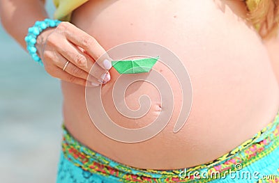 Pregnant woman tummy with paper boat outdoors