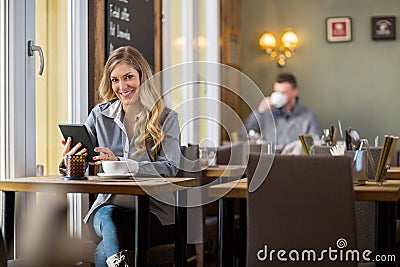 Pregnant Woman Using Digital Tablet In Coffeeshop
