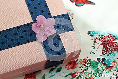 Present box with a blue ribbon and a violet flower