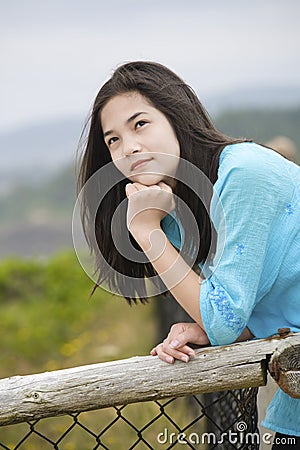 Preteen girl by ocean shore with thoughtful look