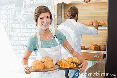 Pretty barista holding trays of baked goods