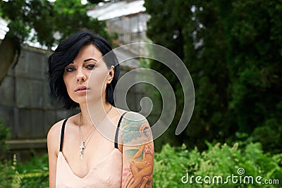 Pretty black haired girl with tattoo in the garden