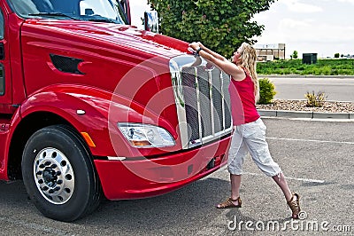 Pretty blonde woman opening a truck hood.