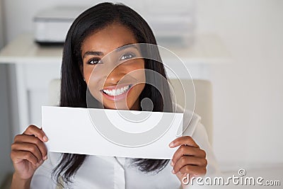 Pretty businesswoman showing white card at her desk