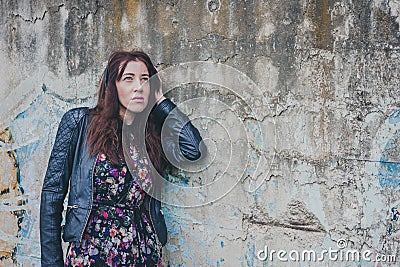 Pretty girl with long hair leaning against a concrete wall
