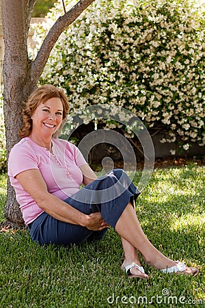 Pretty, middle-aged woman sits under tree