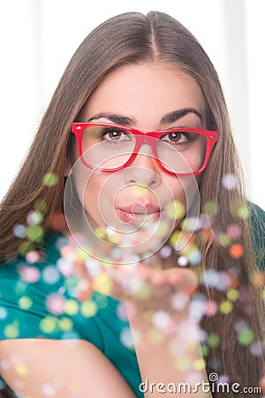 Pretty woman blowing colorful sequins.