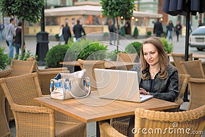 Pretty woman sitting in street cafe with laptop