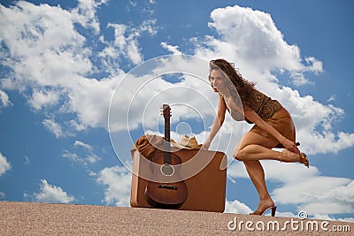 Pretty woman with suitcase and guitar