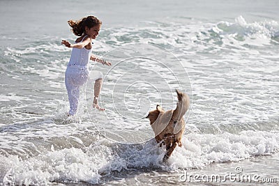 Pretty young girl runs with a dog in the sea water