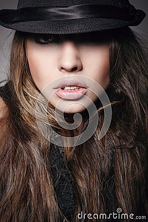 Pretty young woman in black hat looking at camera