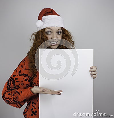 Pretty young woman wearing Santa hat and holding blank sign