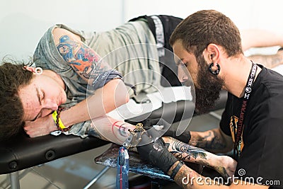 Professional artist doing tattoo on client arm