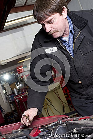 Automotive Technician Works Under the Car Hood in Auto Repair