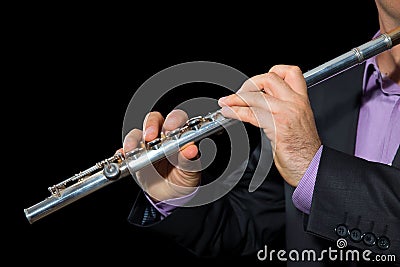 Professional flutist musician playing flute on black background