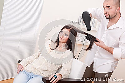 Professional hairdresser with hair dryer at salon