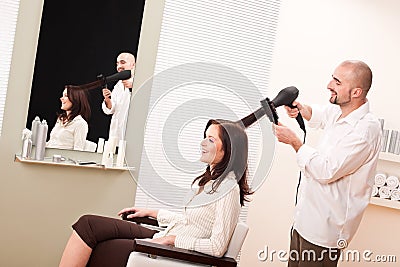 Professional hairdresser with hair dryer at salon