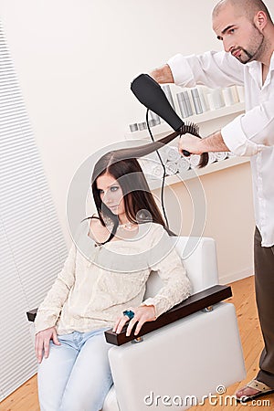 Professional hairdresser with hair dryer at salon
