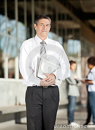 Professor With Book Standing On University Campus