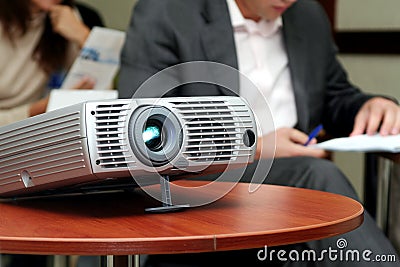 Projector on table with two person behind