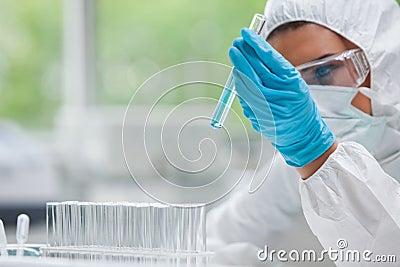 Protected science student looking at a test tube