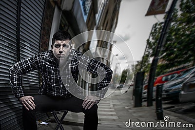 Provocative self-confident man sitting at the street in ready to stand up and fight pose