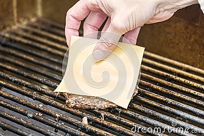 Putting cheese on a grilled hamburger