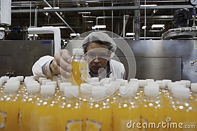 Quality control worker checking juice bottle on production line