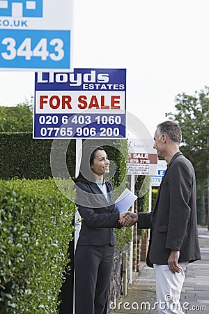 Real Estate Agent And Man Shaking Hands By Sale Signs