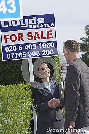 Real Estate Agent And Man Shaking Hands By Sale Signs