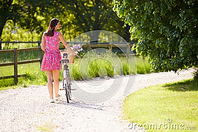 Rear View As Woman Pushes Bike Along Lane