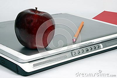 Red apple on laptop with book and pencil