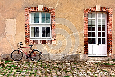 Red Bicycle Leaning against an Old Farmhouse Wall