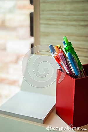 A red box of pens is beside white blank paper